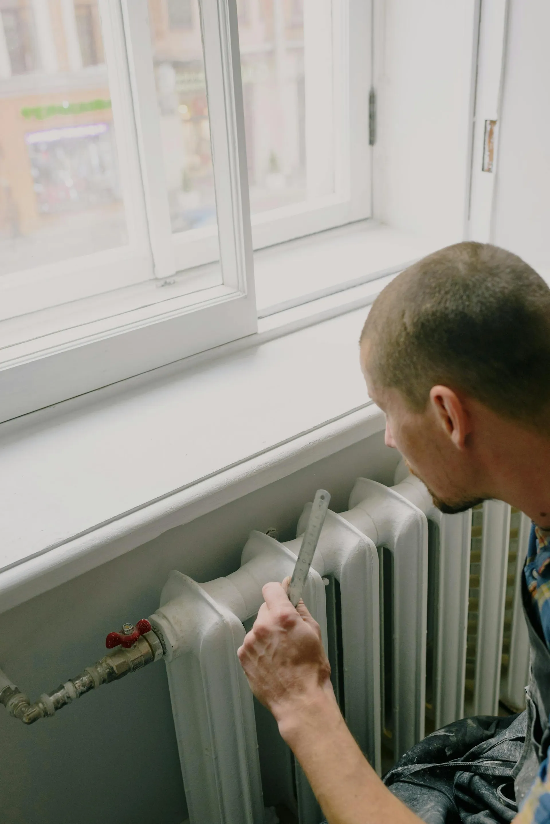Plumber checking a radiator at a residential window