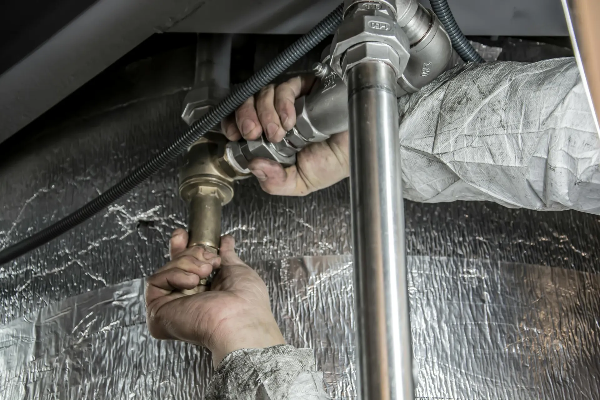 Plumber fitting brass pipework under a Luton kitchen sink